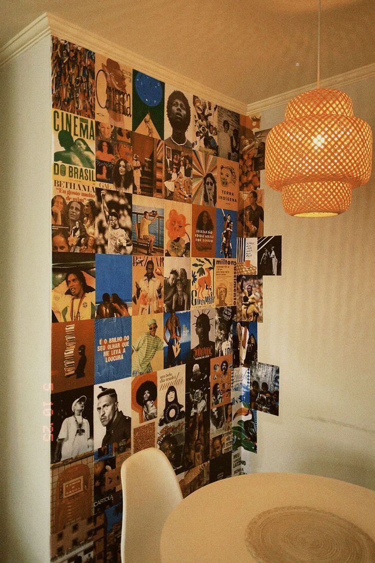 Parede decorada com lambe-lambes de capas de &aacute;lbuns e refer&ecirc;ncias culturais, formando um mural colorido que traz personalidade e estilo art&iacute;stico ao ambiente