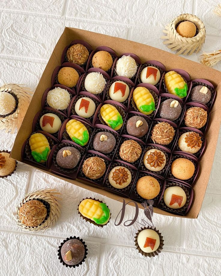 Caixa de doces variados para Festa Junina, com brigadeiros de coco, milho, pa&ccedil;oca, doce de leite e bandeirinhas, sobre fundo branco texturizado