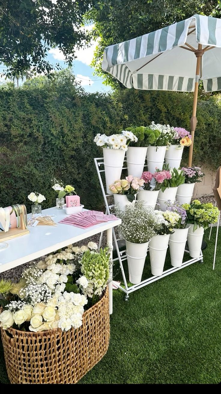 Flower bar ao ar livre com rack de baldes brancos, flores variadas e esta&ccedil;&atilde;o de montagem de buqu&ecirc;s