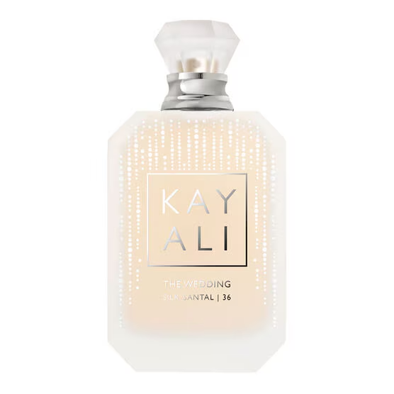 Frasco de perfume Kayali The Wedding Silk Santal 36, retangular com bordas chanfradas, l&iacute;quido bege claro, tampa transparente facetada e detalhes prateados. O nome Kayali est&aacute; em destaque dentro de um quadrado prateado no centro, com pontos brancos verticais nas laterais do frasco