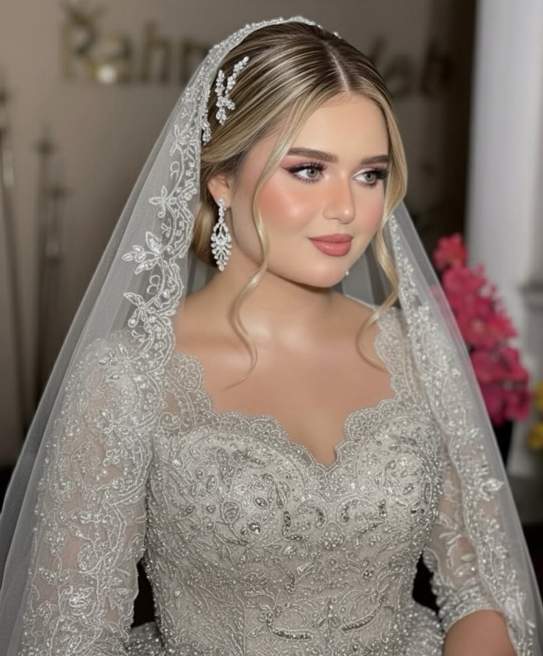 Foto de uma noiva. Ela tem cabelo loiro, usa uma maquiagem leve e um vestido e v&eacute;u rendados