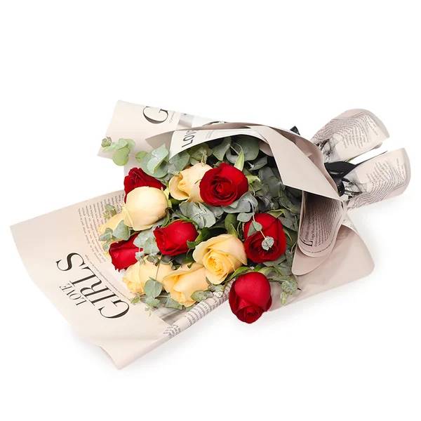 Buqu&ecirc; de rosas vermelhas e amarelas, com folhas verdes de eucalipto, embrulhado em papel bege com letras pretas e amarrado com fita preta, sobre fundo branco