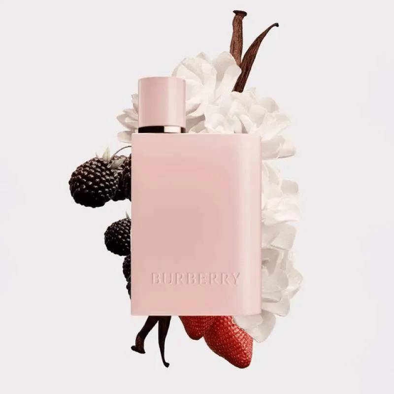 Frasco retangular rosa claro do perfume Burberry, com tampa cil&iacute;ndrica. Ao redor, flores brancas, amoras escuras, morangos vermelhos e favas de baunilha marrons, em fundo branco