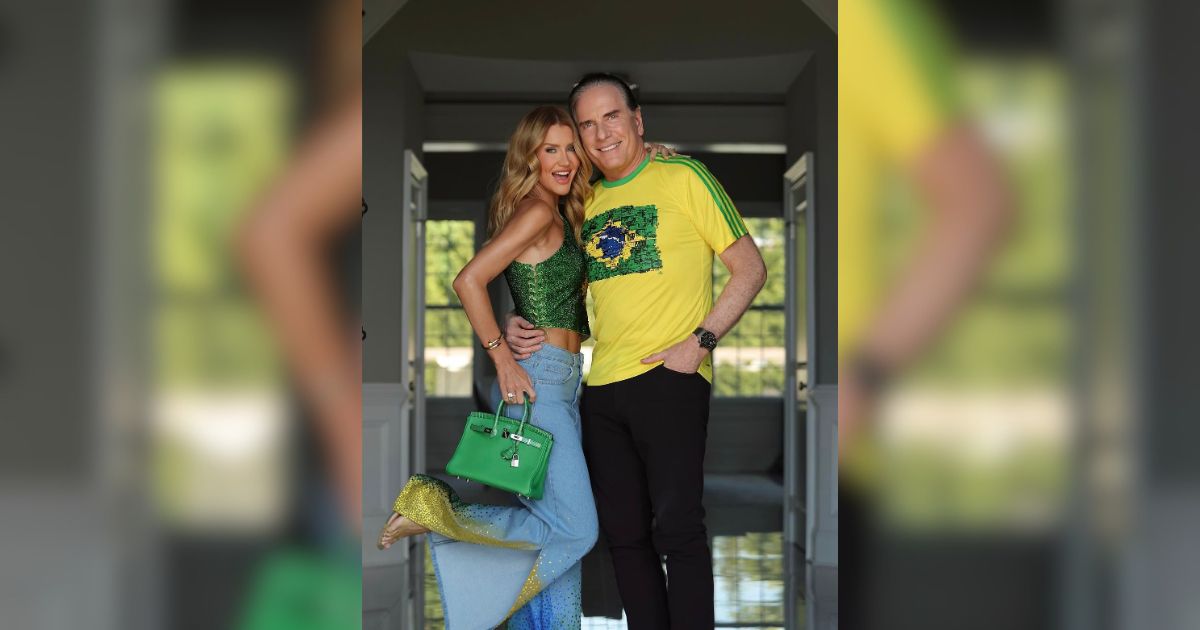 Um casal sorridente posa abra&ccedil;ado em um corredor. A mulher, &agrave; esquerda, usa um top verde brilhante, cal&ccedil;a jeans clara e segura uma bolsa verde. O homem, &agrave; direita, veste uma camisa amarela com a bandeira do Brasil e cal&ccedil;a preta