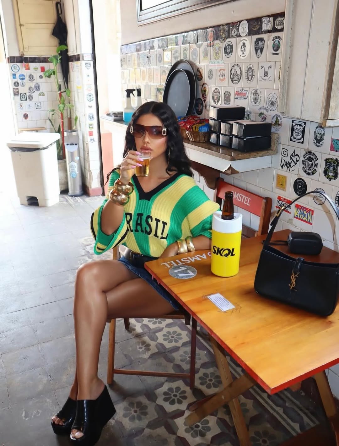 Mulher de &oacute;culos escuros e blusa verde e amarela com a palavra 