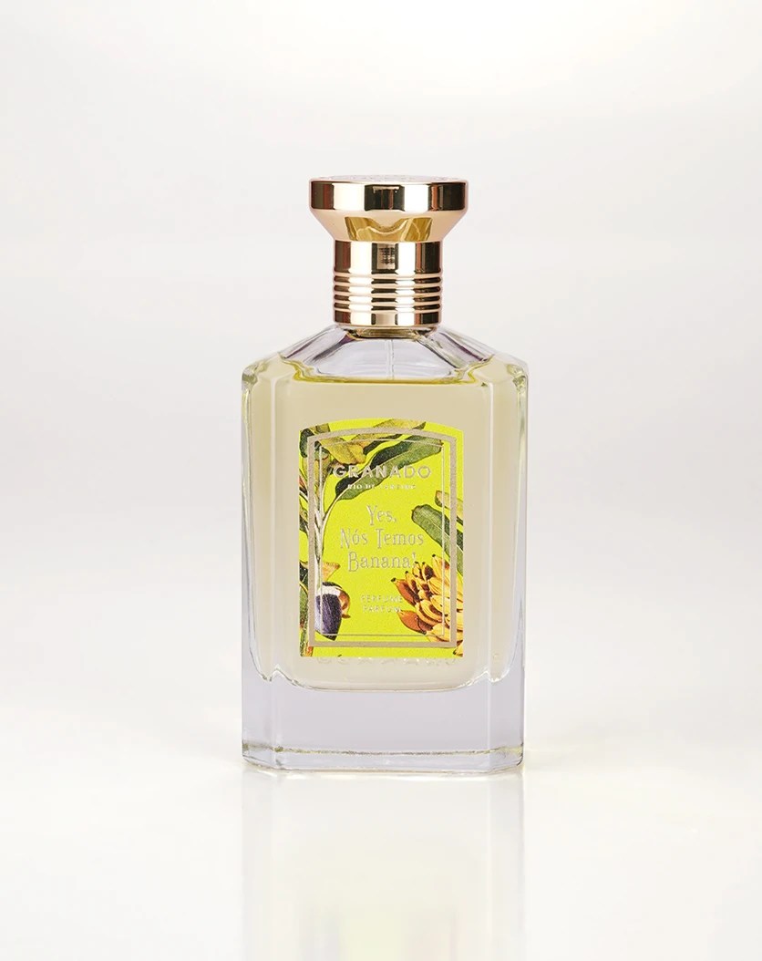 Frasco de perfume Granado retangular com l&iacute;quido amarelo claro, tampa dourada e r&oacute;tulo vibrante com folhas e cachos de banana, escrito Yes, N&oacute;s Temos Banana!