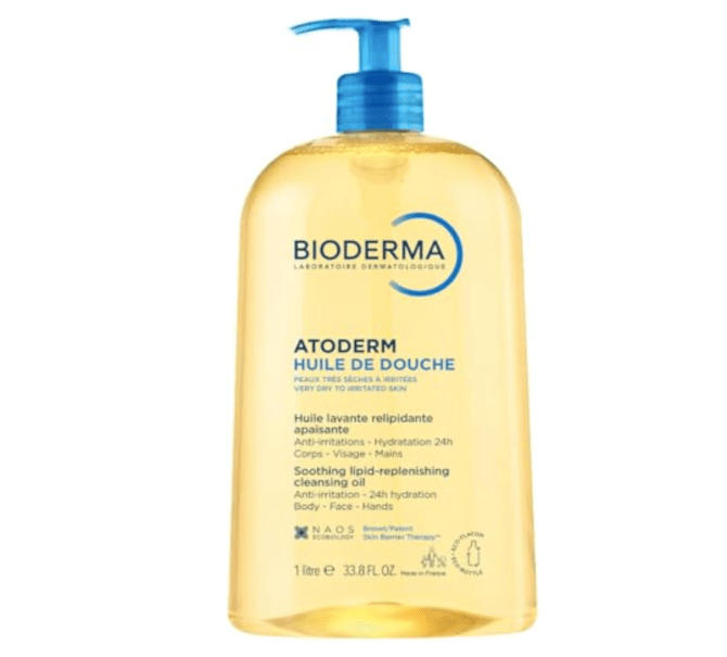 Frasco grande de &oacute;leo de banho Bioderma Atoderm Huile de Douche, com l&iacute;quido amarelo claro e tampa azul de pump, em fundo branco. O r&oacute;tulo informa que &eacute; para peles muito secas e irritadas, com 1 litro de produto