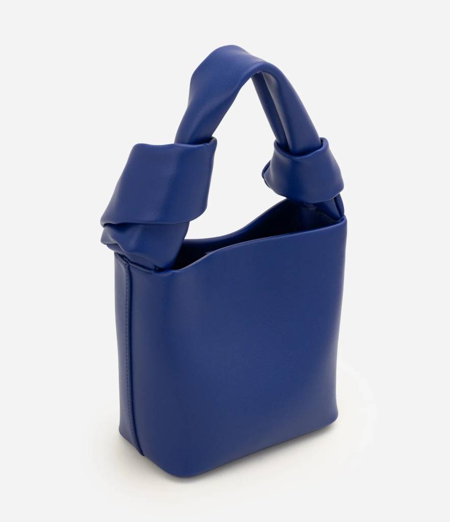 Bolsa feminina azul-royal de couro sint&eacute;tico, com al&ccedil;a curta e larga, torcida em n&oacute;s nas laterais, sobre fundo branco