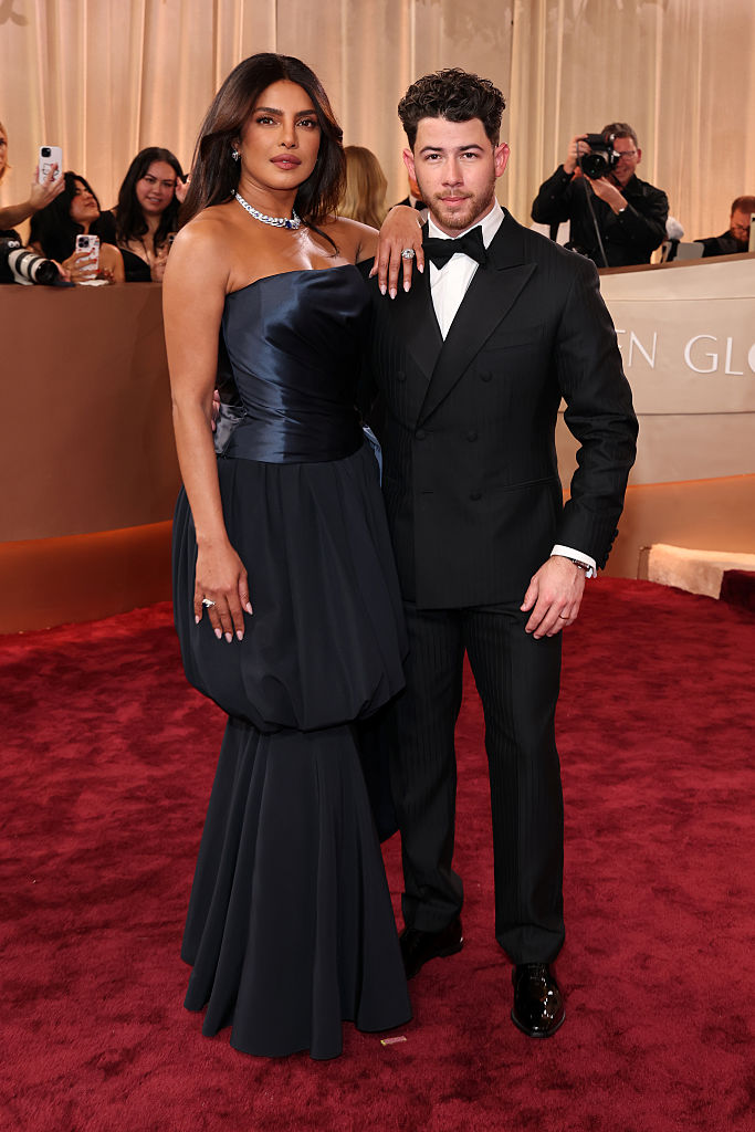 Priyanka Chopra, com vestido tomara que caia azul-marinho e colar de diamantes, posa com Nick Jonas, de smoking preto e gravata borboleta, em tapete vermelho