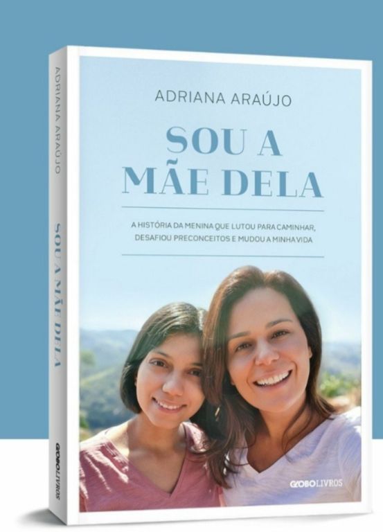 Capa do livro Sou a M&atilde;e Dela de Adriana Ara&uacute;jo, com a autora e uma jovem sorrindo, em um cen&aacute;rio natural. O texto descreve a hist&oacute;ria de uma menina que lutou para caminhar e desafiou preconceitos