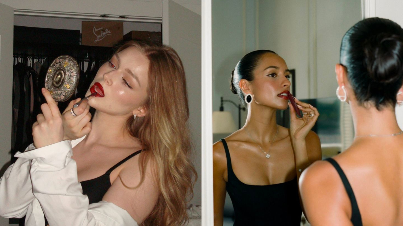 Duas mulheres se maquiando: à esquerda, uma mulher loira de olhos fechados aplica batom vermelho, segurando um espelho decorado; à direita, uma mulher de pele morena com coque e brincos grandes aplica batom marrom, refletida em um espelho
