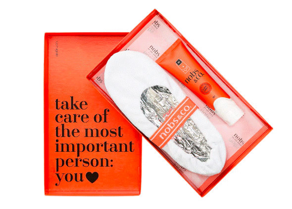 Caixa de presente laranja com a frase take care of the most important person: you e um cora&ccedil;&atilde;o preto. Dentro, um par de meias brancas com embalagem prateada e uma faixa laranja nobs & co., ao lado de um tubo de creme laranja da mesma marca