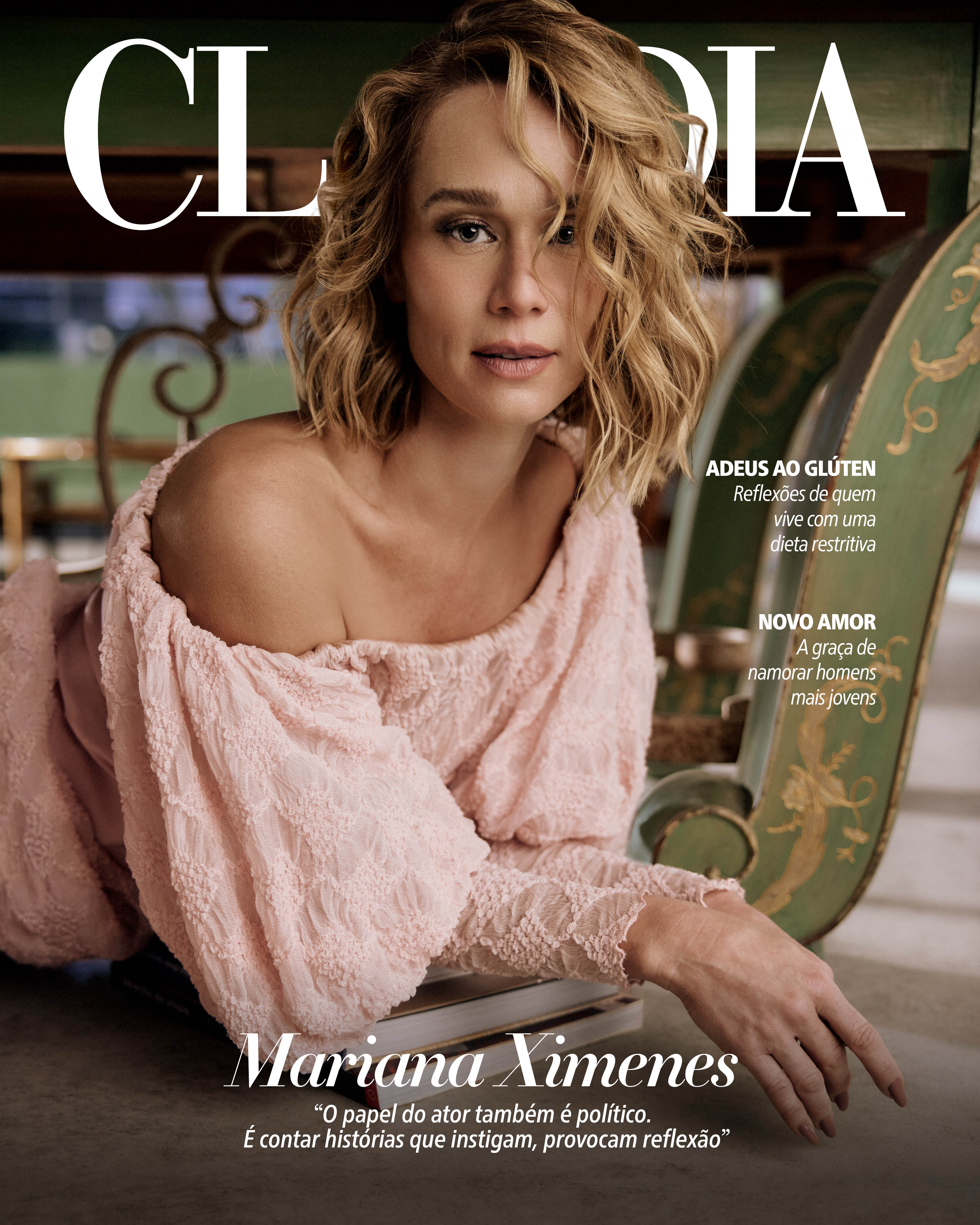 Mariana Ximenes, com cabelos loiros ondulados e maquiagem leve, posa para a capa da revista Claudia. Ela veste uma blusa rosa claro de renda com ombros &agrave; mostra, apoiando-se em uma cadeira verde ornamentada. O olhar &eacute; direto para a c&acirc;mera, com uma express&atilde;o serena. T&iacute;tulos na capa incluem ADEUS AO GL&Uacute;TEN, NOVO AMOR e uma cita&ccedil;&atilde;o da atriz sobre o papel pol&iacute;tico do ator