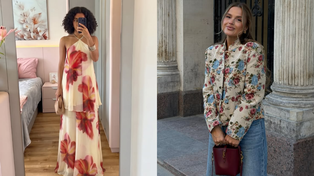 Duas mulheres posam com roupas florais. À esquerda, uma mulher de cabelo cacheado escuro tira selfie no espelho, usando vestido longo creme com flores vermelhas e bolsa bege. À direita, uma mulher loira sorri, vestindo blazer floral creme com flores azuis e vermelhas, calça jeans e bolsa vinho, em frente a uma coluna de pedra