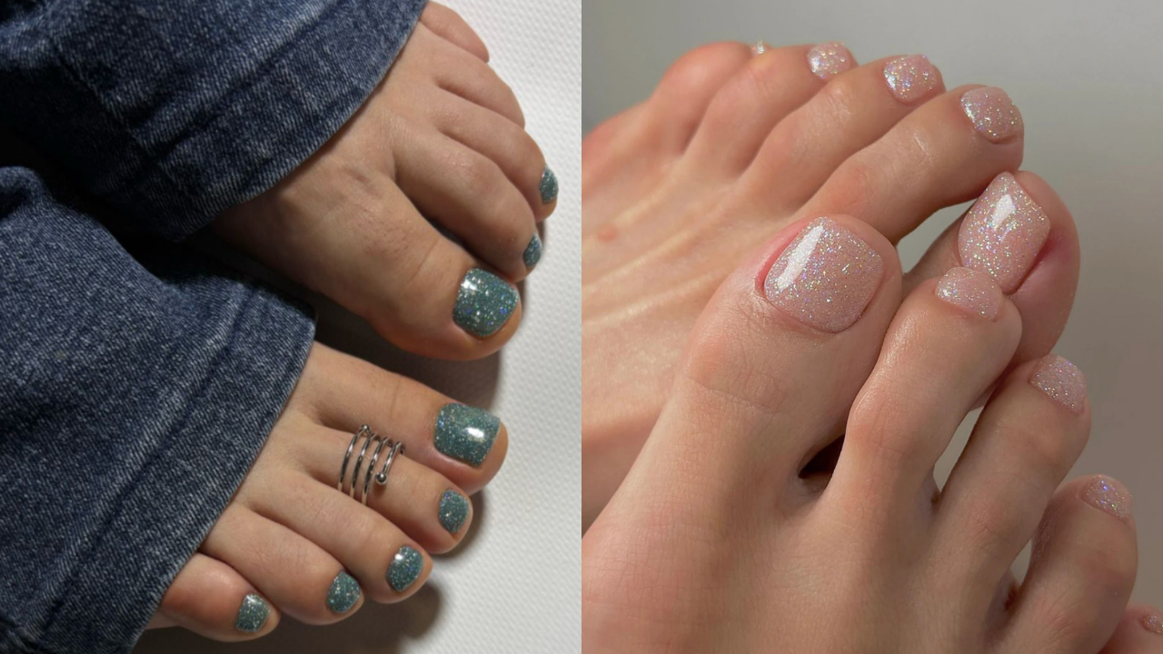 Dois pés com unhas esmaltadas com glitter. O pé esquerdo tem esmalte azul-acinzentado e um anel de dedo prateado. O pé direito tem esmalte nude com glitter e uma linha branca diagonal no dedão