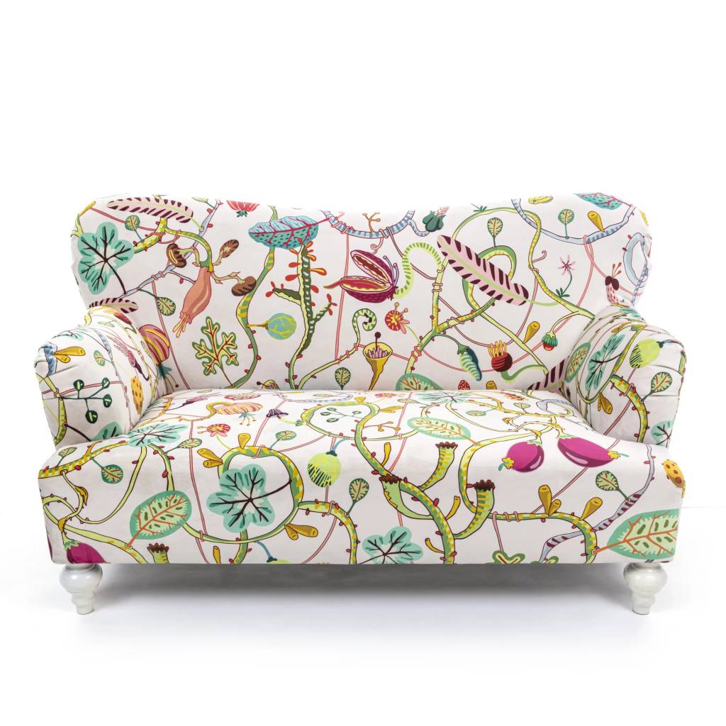 Sof&aacute; de dois lugares com estampa floral colorida em fundo branco, exibindo galhos, folhas e flores em tons de verde, rosa, azul e amarelo. Possui p&eacute;s brancos arredondados.