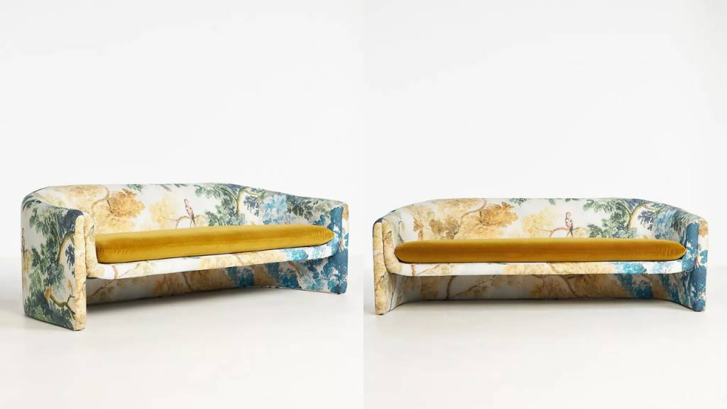 Dois sof&aacute;s id&ecirc;nticos, estofados com tecido estampado em tons de azul, verde e amarelo, com almofadas de assento amarelas. O padr&atilde;o do tecido mostra &aacute;rvores e p&aacute;ssaros em estilo toile de Jouy